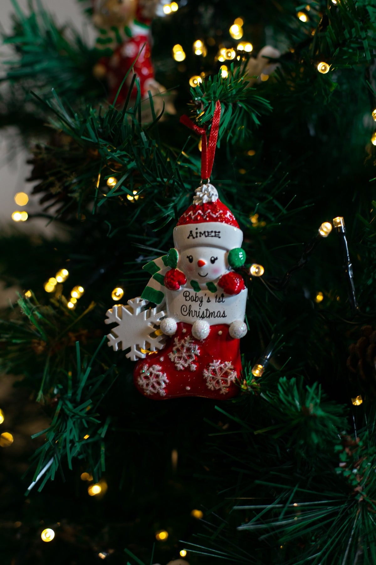 Baby Snowman in Stocking (Red) hanging on a Christmas tree