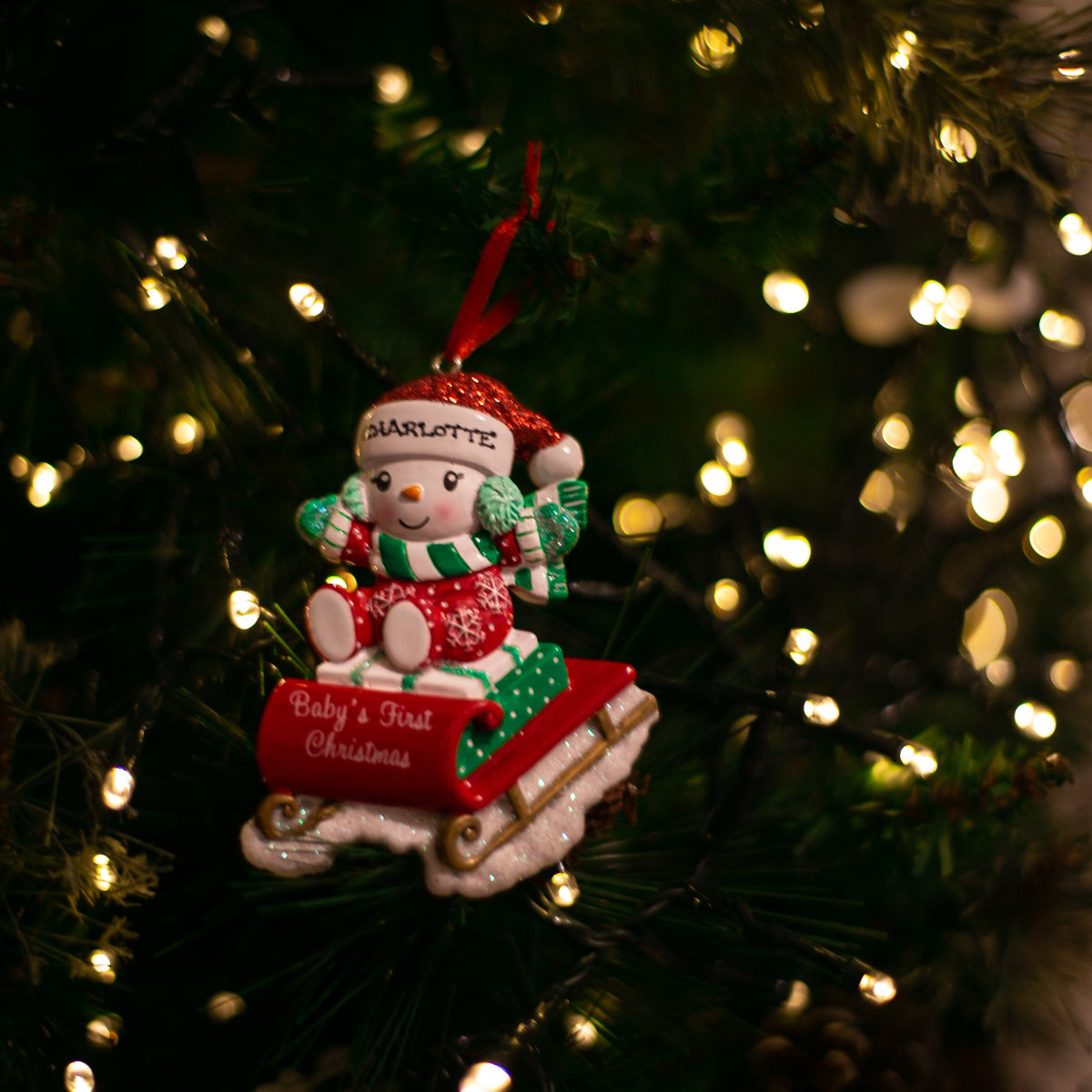 Snowbaby on Sled - Red and Green hanging on a Christmas tree