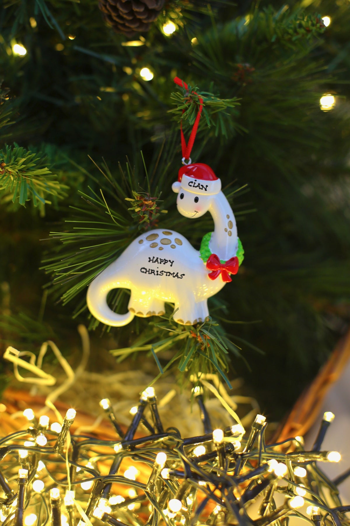 White Dino with Wreath Personalised Christmas Decoration hanging on a Christmas tree